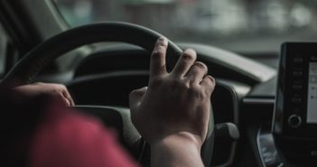 person's hand on car steering wheel