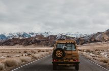 rear view of SUV traveling on road with mountains in background
