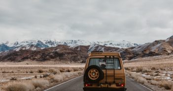 rear view of SUV traveling on road with mountains in background
