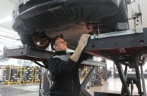 mechanic working on engine standing under vehiccle