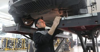 mechanic working on engine standing under vehiccle