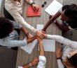 overgead view of coworkers putting their hands together over a table