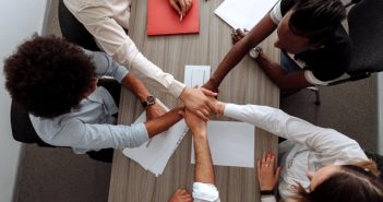 overgead view of coworkers putting their hands together over a table