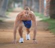 muscular man in blue shorts on dirt road working out