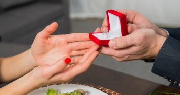 close-up of man giving woman engagement ring in red box