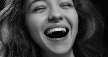 pretty woman with nice teeth close-up with closed eyes and open smile