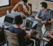 workers with laptop around table in office