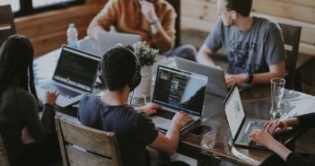 workers with laptop around table in office