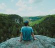 rear view of man sitting on a rock looking out at nature