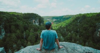 rear view of man sitting on a rock looking out at nature