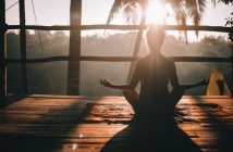rear silhouette view of woman doing yoga at sunrise