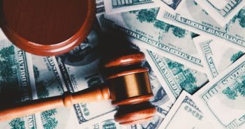 wooden gavel on top of paper money