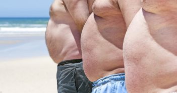 three shirtless men with bellies on the beach