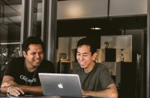 two men working at desk with laptop