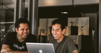 two men working at desk with laptop