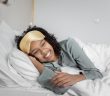 pretty woman smiling and laying in bed with white sheets