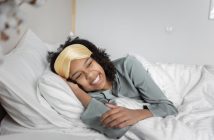 pretty woman smiling and laying in bed with white sheets