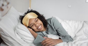 pretty woman smiling and laying in bed with white sheets
