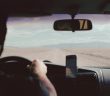 view of man driving car over his shoulder looking out onto the road