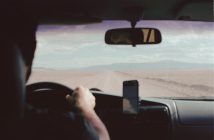 view of man driving car over his shoulder looking out onto the road