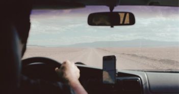 view of man driving car over his shoulder looking out onto the road