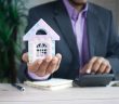 man in suit holding toy house