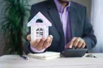 man in suit holding toy house