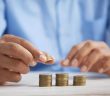 closeup of man's hands stacking coins on table