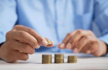 closeup of man's hands stacking coins on table