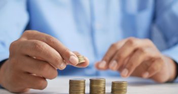 closeup of man's hands stacking coins on table