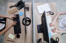 overhead shot of office workers at desk working on PCs