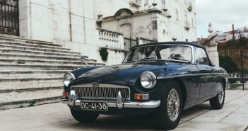 classic car next to stairs of old stone building