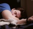 man sleeping in bed with blue shirt and white sheets