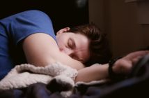 man sleeping in bed with blue shirt and white sheets