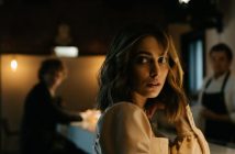 woman at bar with man in background