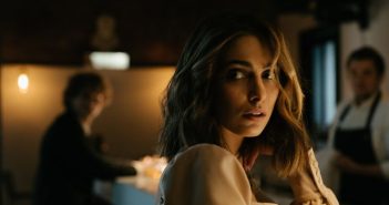 woman at bar with man in background