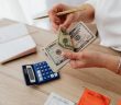 close-up of woman's hands holding money over desk