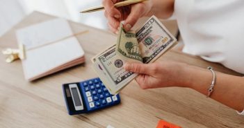 close-up of woman's hands holding money over desk