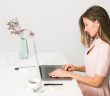 pretty brunette woman sitting at desk on laptop