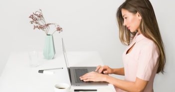 pretty brunette woman sitting at desk on laptop