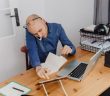 man sitting at desk with laptop on the phone
