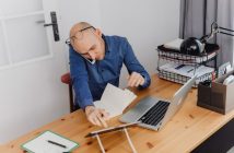 man sitting at desk with laptop on the phone
