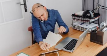 man sitting at desk with laptop on the phone