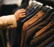 men's suits on the rack with hand reaching in