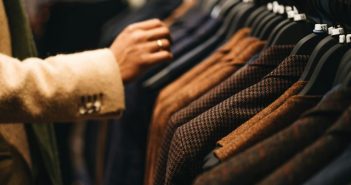 men's suits on the rack with hand reaching in