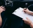 person writing on clipboard inside car