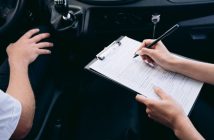 person writing on clipboard inside car