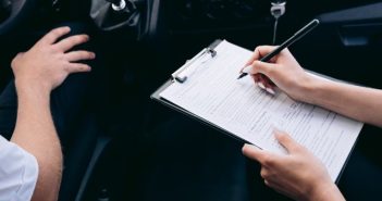person writing on clipboard inside car