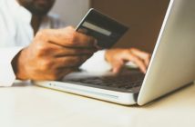 man holding credit card while typing into laptop