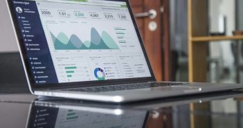 laptop on glass table with website statistics